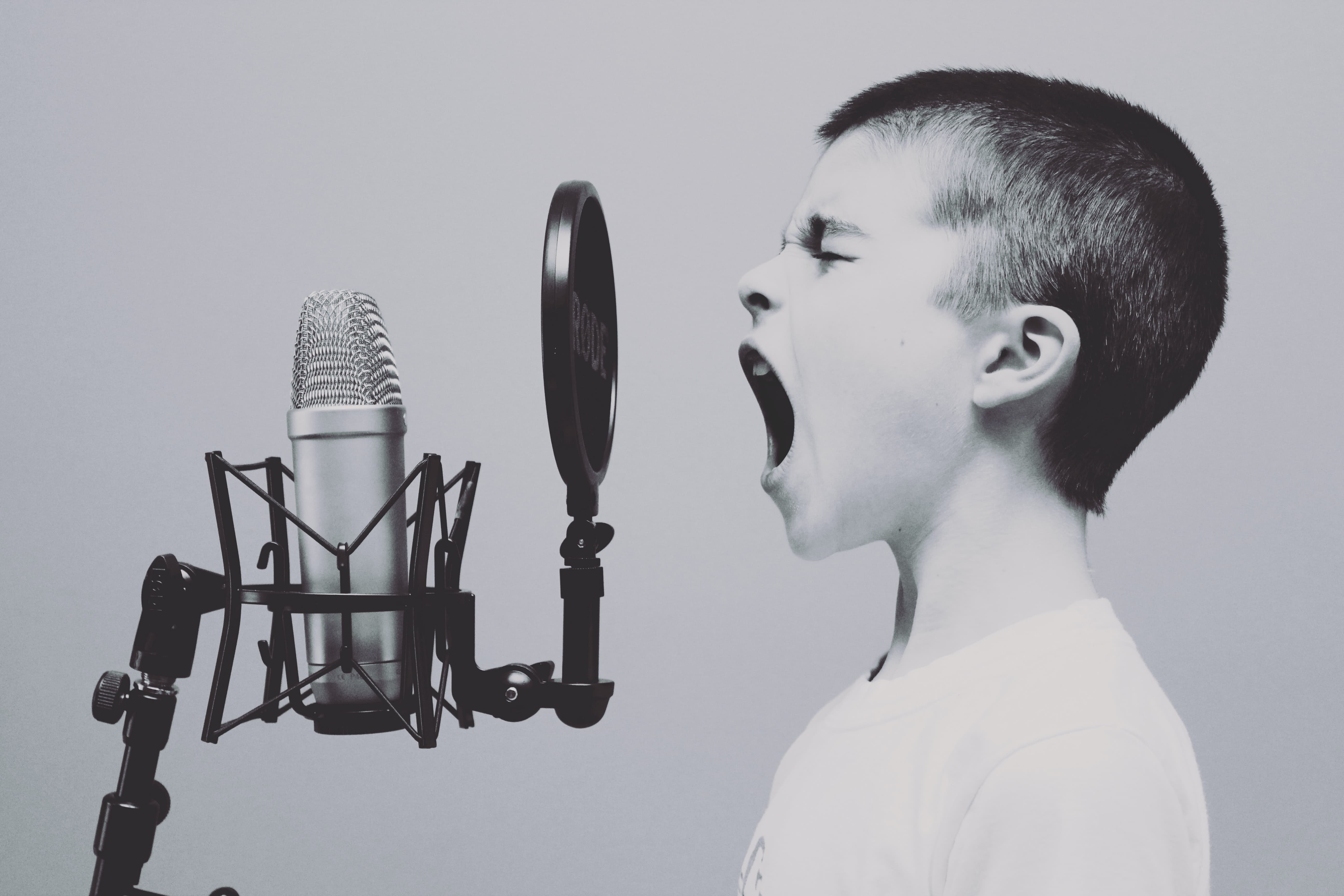 A young short haired kid yells into a microphone